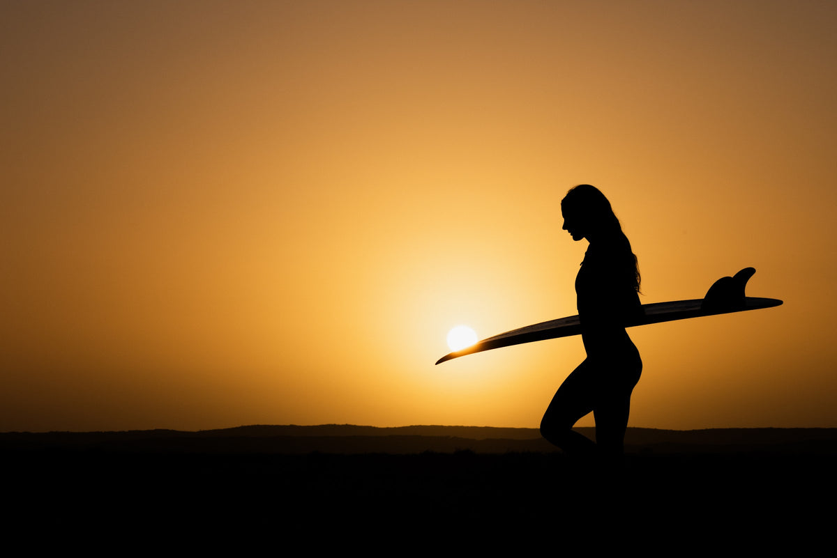 Surfista con su tabla al atardecer